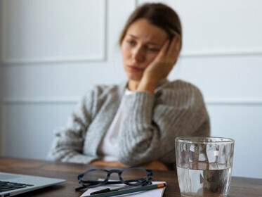 A woman sitting on a chair, looking distressed by her financial problems