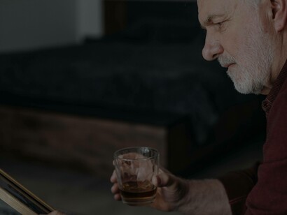 A man taking comfort in a glass of whiskey as he looks at those who didn't survive the near-death experience