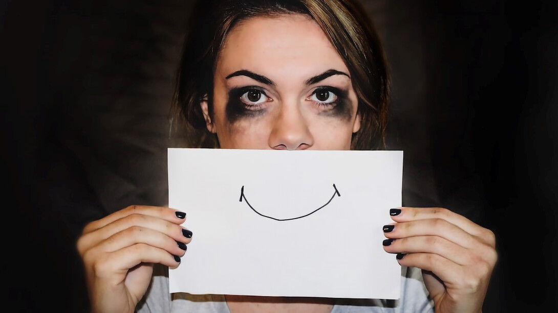 A woman, initially in tears, now holds a paper with a smiley face in front of her, symbolizing her changing emotions and resilience
