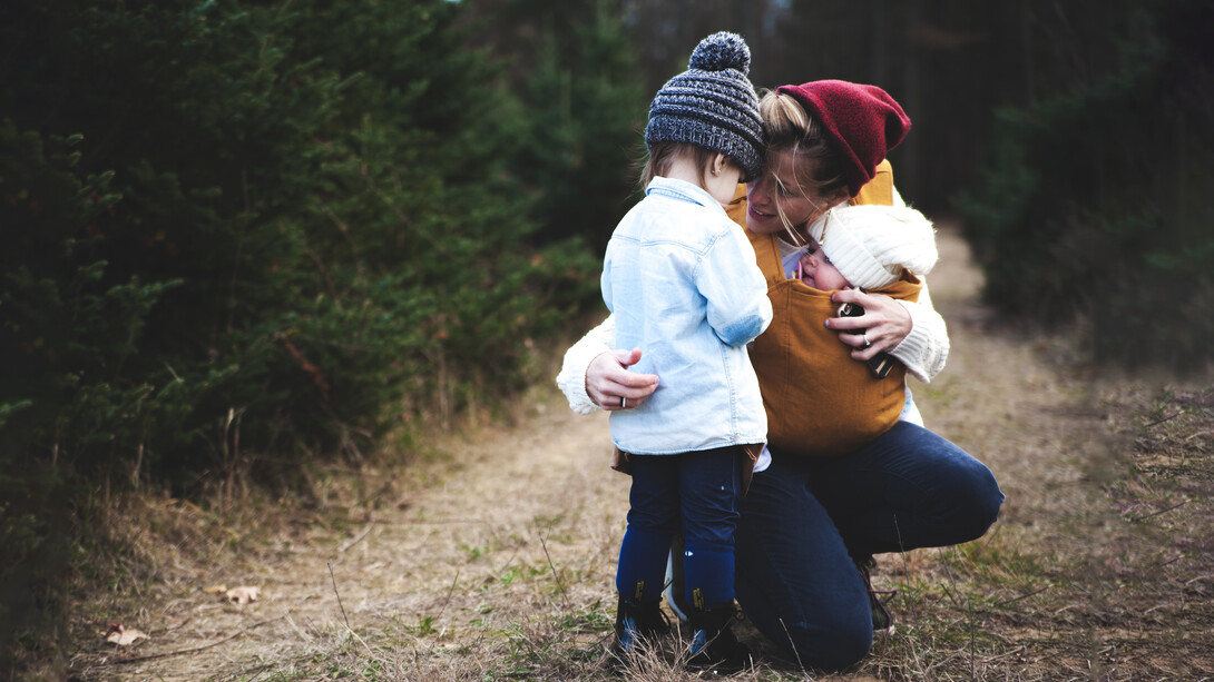 Una madre con sus hijos en la vereda de un bosque