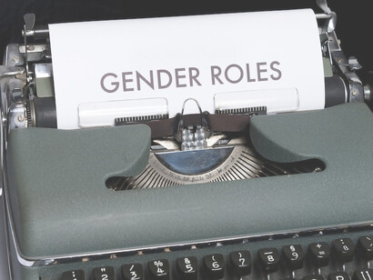 Adjacent to the typewriter, there lies a sheet of paper imprinted with the words "gender roles"