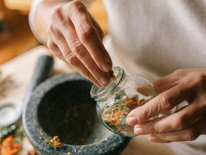 A traditional Ayurvedic preparation: dried flowers being ground with a mortar and pestle, representing natural detox and ancient healing practices