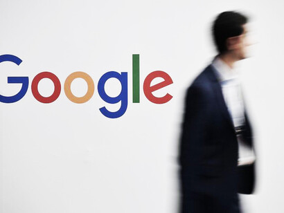 Un hombre camina delante del logo de Google