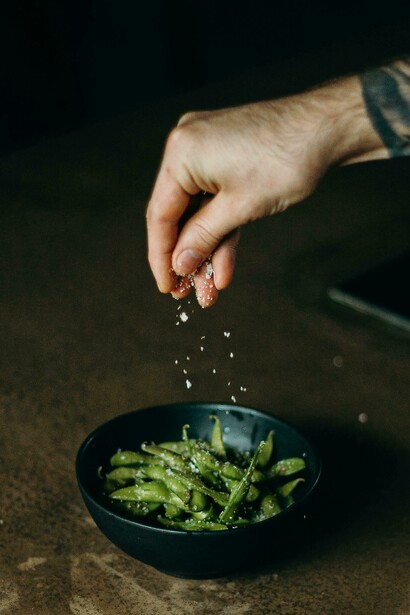 Cooking sweet peas and green beans with a touch of salt, representing wholesome and healthy vegan snacking