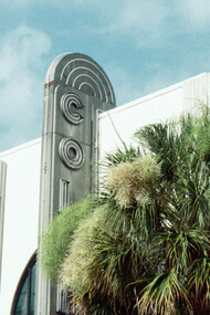 An art deco front face of a Miami building, and their notable palm trees