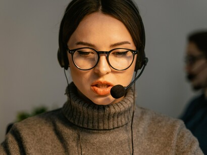 A headset-wearing support agent focused on a customer interaction, representing the trusted help desk role that cybercriminals increasingly impersonate