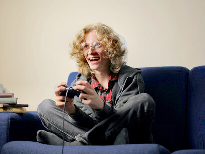 Jovem se distrai jogando videogame no console de TV
