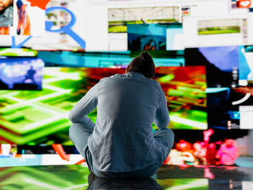 Person surrounded by screens, overwhelmed by online presence