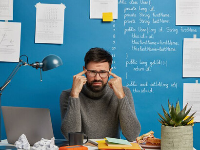 Exhausted and stressed, a software developer stares at his screen—burnout creeping in after another intense day of debugging