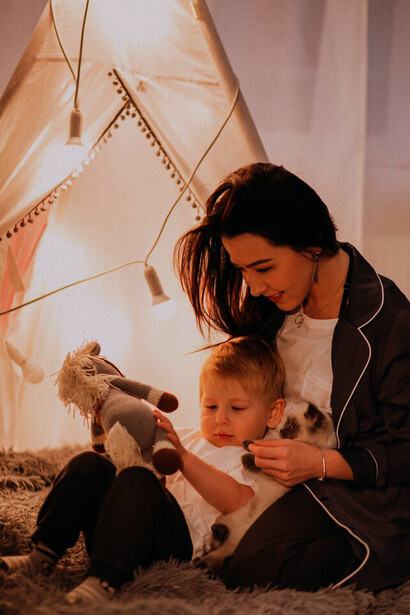 A mother and her son sitting in a cozy, light-filled tent at home on Christmas, sharing a heartfelt moment of reflection