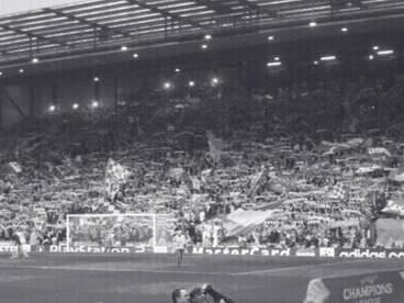 Une nuit européenne magique à Anfield. Les supporters des Reds dans le célèbre Kop lors d'une rencontre de Ligue des Champions, entourés de drapeaux et d'écharpes celebrant le Liverpool FC