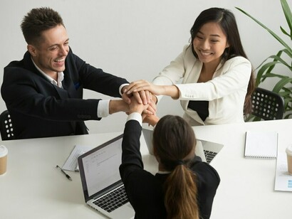 A dynamic millennial office team celebrating with high fives, reflecting teamwork, workplace equity, and the spirit of inclusivity in a multicultural environment