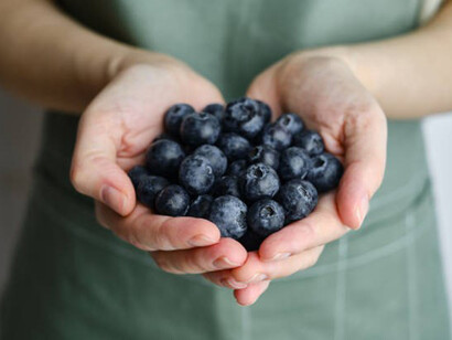 A woman is holding a handful of blueberries