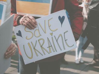 A sign that reads "Save Ukraine" is being held in the streets of Ukraine