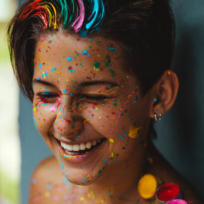 Mulher adulta feliz ao deixar se sujar com diferentes cores de tinta
