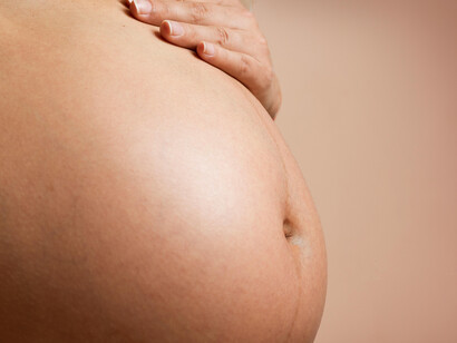 A pregnant woman’s hand rests gently on her belly