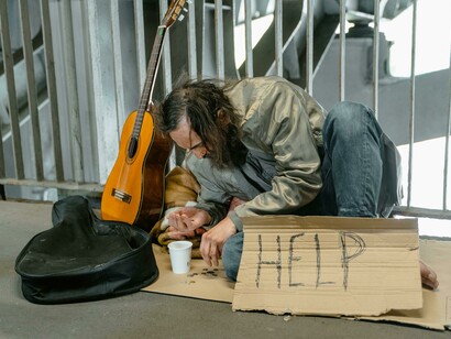 Bearded man sitting on the ground, reflecting the human cost of poverty