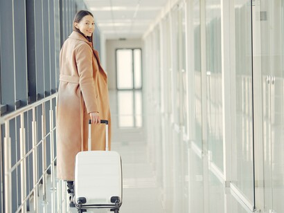 Elegante viajante feliz com mala no corredor do aeroporto