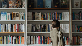 Una joven revisando una biblioteca, a punto de reencontrarse con la necesaria reedición de una obra