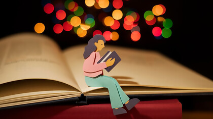 A cartoon of a paper woman reading a book on book