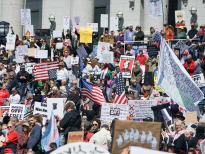 A crowd of protesters holds signs during a demonstration against Donald Trump and Elon Musk outside the Utah State Capitol, USA