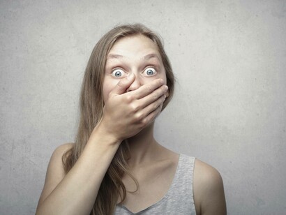 A woman with hand over mouth out of fear