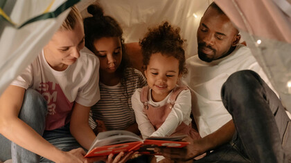 Família brasileira interracial desfrutando da leitura de um livro físico juntos