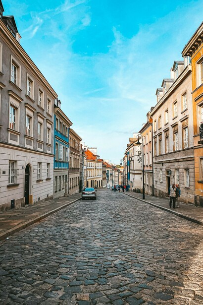 People strolling through the Old Town Market Square in Warsaw, Poland, surrounded by historic buildings on a bright, sunny day