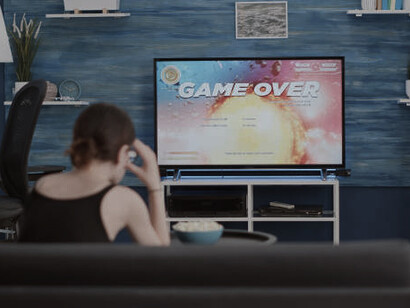 Sitting on the couch in her living room, a woman watches the live news, visibly stressed and overwhelmed by the political developments unfolding