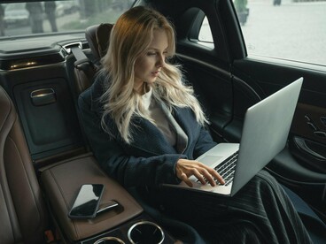 A woman turning travel time into work time, symbolizing how busyness extends beyond the workplace