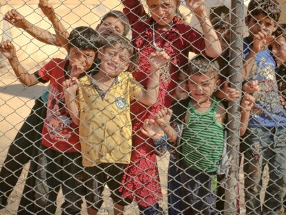 Children await for goods to arrive behind a fence