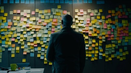 A man staring at a board filled with colorful adhesive notes after a brainstorming session