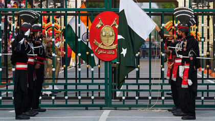 Soldados de Pakistán, vestidos de negro, y soldados de las Fuerzas de Seguridad Fronteriza de la India bajan sus banderas durante la ceremonia de clausura diaria en Wagah, un puesto conjunto en la frontera entre ambos países, cerca de Lahore, Pakistán, 3 de mayo de 2025