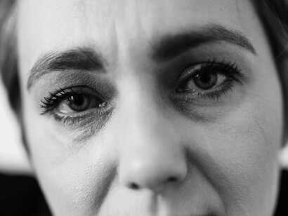 A face clenched in sorrow mirrors the buried children, the flooded tents, and the unspoken names