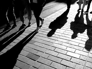 Silhouettes of people walking along the sidewalk in the evening light