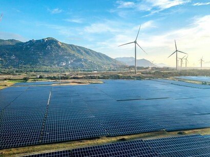 Wind turbines aligned across the horizon alongside solar panels, representing the transformation of energy systems 