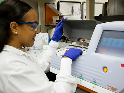 A skilled technician stands poised before a state-of-the-art digital machine amidst a cluster of desktop genomic sequencing machines at the Cancer Genomics Research Laboratory, a vital component of the National Cancer Institute's Division of Cancer Epidemiology and Genetics (DCEG), dedicated to the precise work of DNA genotyping and sequencing