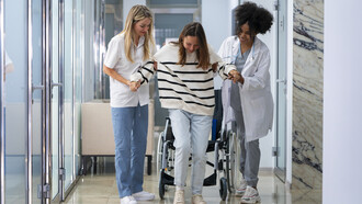 Female doctors assist a patient in a wheelchair with care and professionalism
