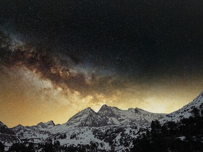 The Milky Way stretching across snow-capped mountain peaks, representing the pristine dark skies that create ideal conditions for meteor spotting