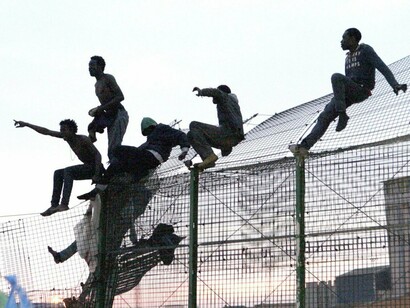 Emigrantes africanos saltando la valla de Melilla