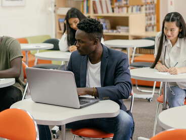 Attentive student using a laptop in a bright and modern classroom setting