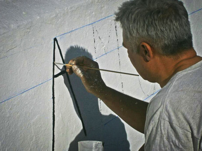 Un hombre escribe un poema sobre una pared