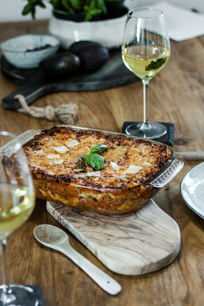A hearty serving of lasagna on a rustic wooden table, paired with a glass of wine