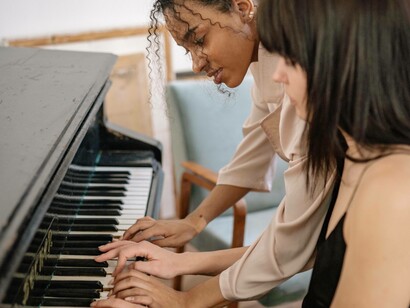 Two woman learning how to play the piano in tandem