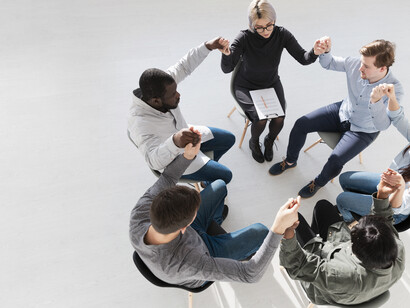 Top view of people standing in a circle with raised hands, symbolising cooperation, human connection, and social networks