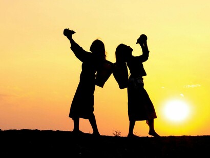 Two people dancing together at sunset, highlighting the strength in unity. Working alone may negatively impact both work performance and mental well-being