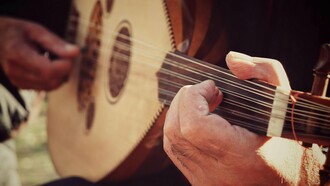 Weathered hands gliding across the oud’s strings, representing the preservation of Morocco’s musical memory