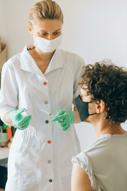 A healthcare professional prepares to administer a vaccine to a patients