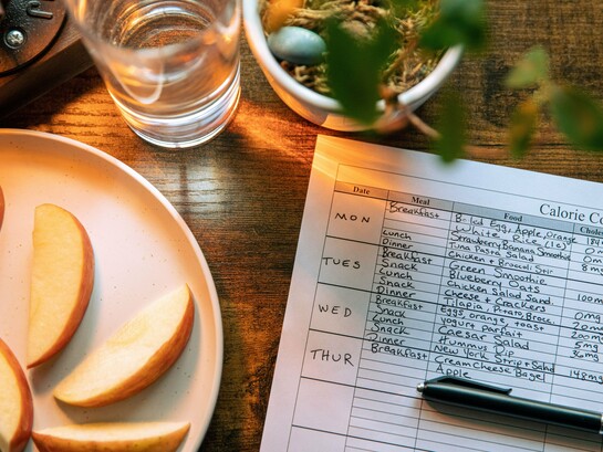 A plate of fresh fruit beside a calorie and nutrition chart, representing the role of food security in protecting health and development