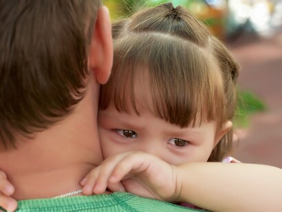 Una niña llora sobre el hombro de su padre